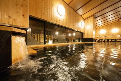 a swimming pool with a water fountain in a building at Hida Takayama Onsen Hida Hotel Plaza in Takayama