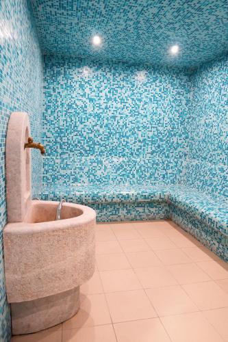 a bathroom with a toilet in a room with blue tiles at Garden City Hotel Konjic in Konjic
