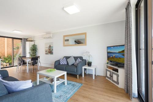 a living room filled with furniture and a tv at Hydra Holiday Units in Merimbula