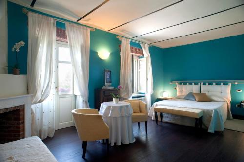 a bedroom with blue walls and a bed and a table at Hotel Cascina Di Corte in Venaria Reale