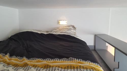 a bedroom with a bed with a black and yellow comforter at LE STULLEDIO tt confort et très bien situé a deux pas du centre ville in Tulle