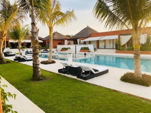 a resort with a pool with lounge chairs and palm trees at Villa Le Petit Paradis Saly Boutique Hotel in Ngaparou