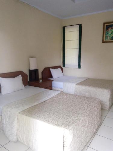 a hotel room with two beds and a window at Villa Bora Paloma in Perdana