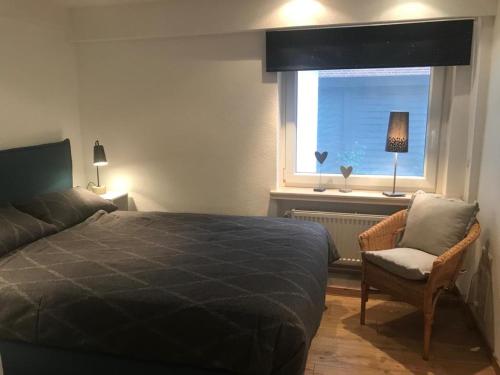ein Schlafzimmer mit einem Bett, einem Stuhl und einem Fenster in der Unterkunft Ferienwohnung Piesch in Glücksburg