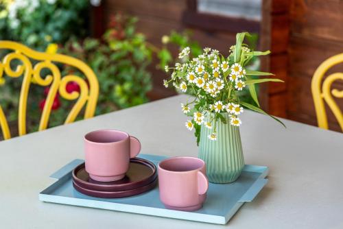 a table with three cups and a vase with flowers at The Village- Jordan Riverside Travel Hotel in Sde Nehemia