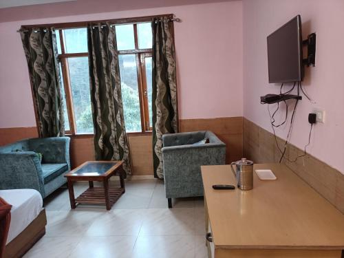 a living room with a table and chairs and a tv at Ivy Stays in Shimla