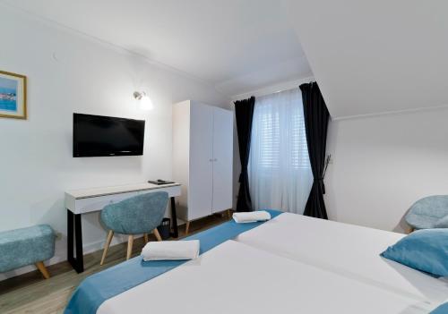 a hotel room with two beds and a desk at Hotel Perla in Dubrovnik