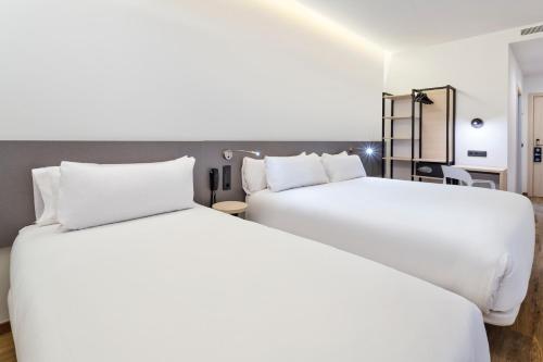 two beds in a hotel room with white sheets at B&B HOTEL Madrid Alcorcón in Alcorcón