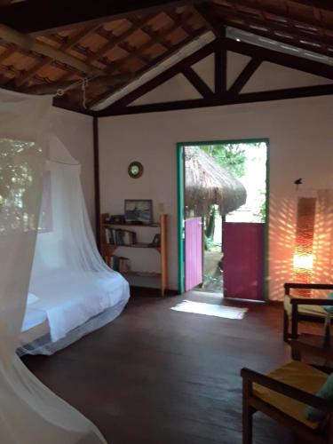 a bedroom with a bed and an open door at Casinha Amarela EcoLodge Boipeba in Ilha de Boipeba