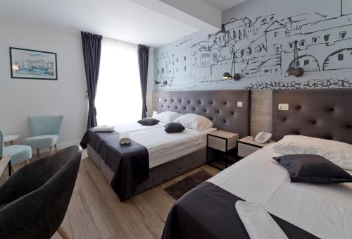 a bedroom with two beds and a wall with drawings on it at Hotel Perla in Dubrovnik