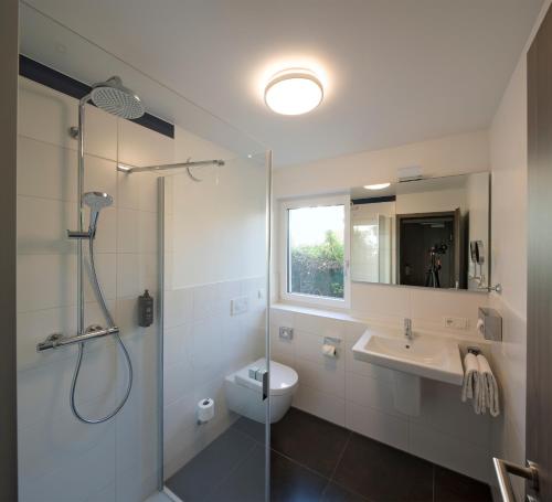 a bathroom with a shower and a toilet and a sink at ANA Living Karlsruhe by Arthotel ANA in Karlsruhe
