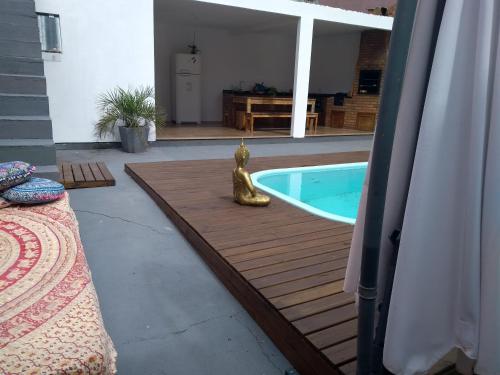 a pool with a statue next to a wooden deck at Casa no Campeche com Piscina in Florianópolis