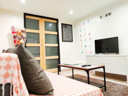 a living room with a couch and a tv and a table at Cosy Paris CDG Stade de France in Le Blanc-Mesnil
