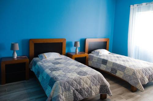 um quarto com 2 camas e uma parede azul em Casa dos cinco sentidos em Feteira Pequena
