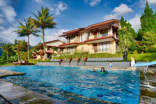 a family swimming in a pool in front of a house at The Jayakarta Cisarua in Puncak