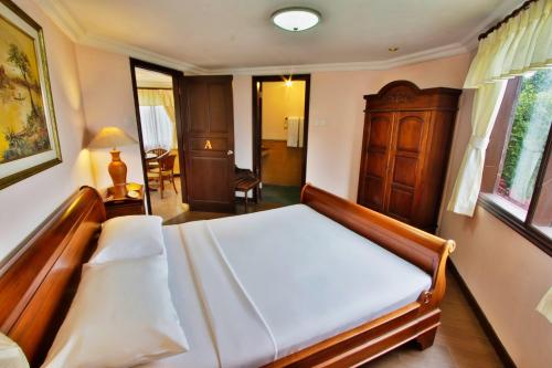 1 dormitorio con 1 cama con cabecero de madera en The Jayakarta Cisarua, en Puncak