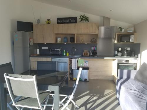 une cuisine avec une table en verre et deux chaises dans l'établissement Un pied devant l'autre, à Sainte-Marie-dʼAlvey