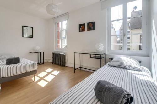a white bedroom with two beds and two windows at MAISON MODERNE ET SPACIEUSE AU CENTRE DE DEAUVILLE in Deauville