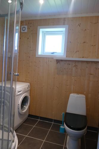 a bathroom with a toilet and a washing machine at Koselig Hytte i Nykvåg in Nykvåg
