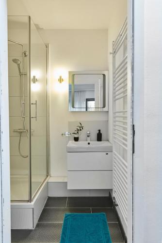 a bathroom with a sink and a shower with a mirror at SCHLAFGUT! HOTEL-WILL.ICH Garni in Willich