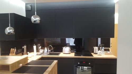 a kitchen with black cabinets and a stove top oven at Apartament Skarbowa 2 in Leszno