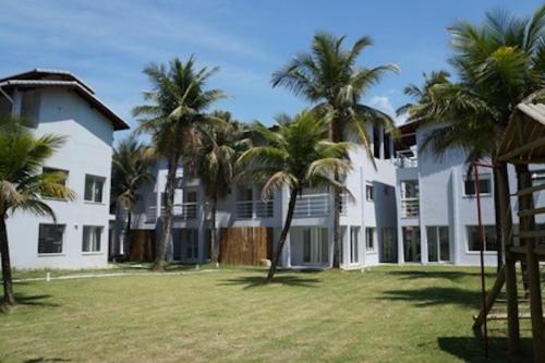 een groot wit gebouw met palmbomen in een tuin bij Casa Pé na Areia em Ubatuba - Alto Padrão a 30m da Praia in Ubatuba