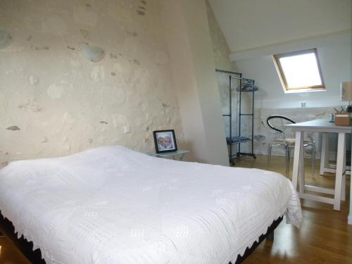 a bedroom with a white bed in a room at Le Logis de la Chouette in Baugé-en-Anjou