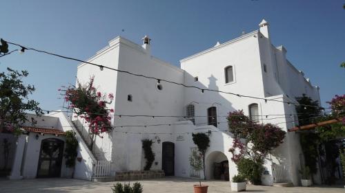 a white building with flowers in front of it at Masseria Parco di Castro in Montalbano