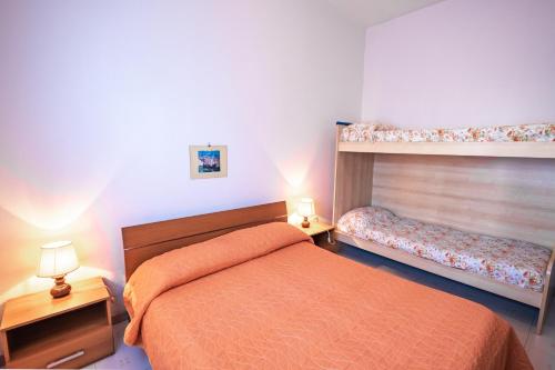 een slaapkamer met een oranje bed en 2 stapelbedden bij Agenzia Vear Villa Marina in Lido delle Nazioni