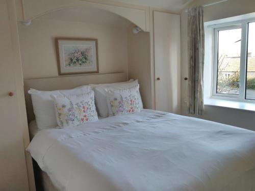 sypialnia z białym łóżkiem z poduszkami i oknem w obiekcie The Lodge w mieście Masham