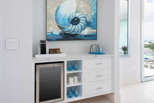 a white entertainment center with a painting on the wall at Zenza Boutique Hotel in Providenciales