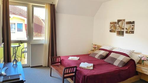 a bedroom with a red bed and a large window at Kála Wellness Apartman in Zalakaros