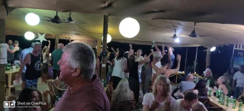 a crowd of people sitting in a bar with their hands in the air at Rococo Pelton beach huts Palolem Beach goa in Palolem