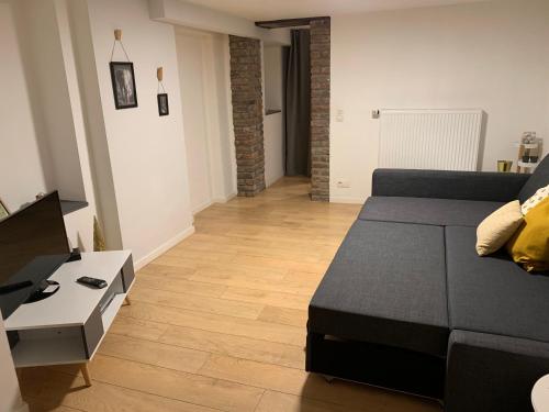 un soggiorno con divano nero e pavimento in legno di Appartement cosy Spa a Spa