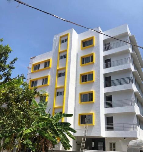 a tall white building with yellow windows on it at Nachiyar Suites in Trivandrum