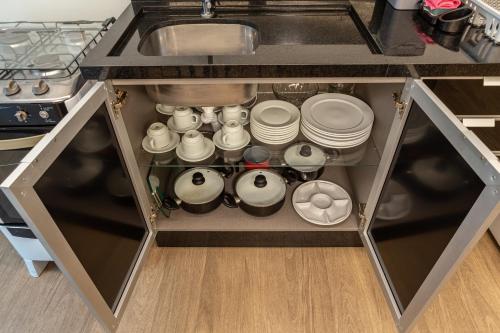 a kitchen cabinet filled with pots and pans at Nilmare Apartamentos e Suites para suas Férias in Itapema