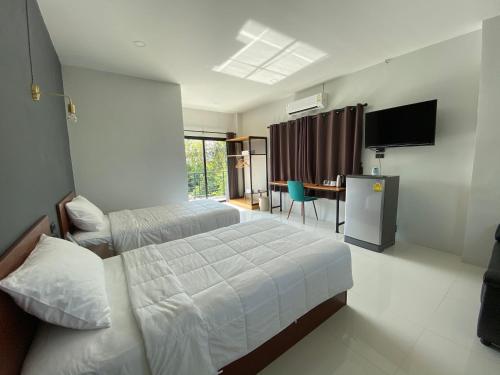 a hotel room with two beds and a television at DD Modern House in Suratthani