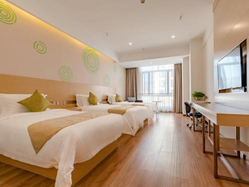 a hotel room with three beds and a desk at GreenTree Inn Taian High-speed Railway Station Lingshan Avenue Business Hotel in Tai'an