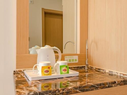 a kitchen counter with a coffee maker and two mugs at GreenTree Inn Taian High-speed Railway Station Lingshan Avenue Business Hotel in Tai'an