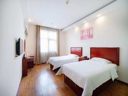 a hotel room with two beds and a television at GreenTree Inn Henan Zhengzhou Chengnan Road Bojue Business Hotel in Zhengzhou