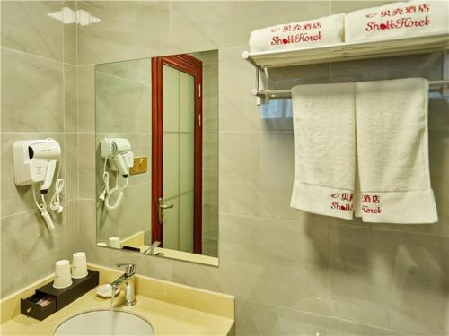 a bathroom with a sink and a mirror and towels at Shell Wuhu City Jinghu District Rehabilitation Road Hotel in Wuhu