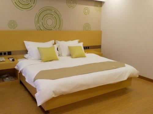a bedroom with a large white bed with green pillows at GreenTree Inn HuaiAn Area for development Shenzhen East Road Express Hotel in Huai'an