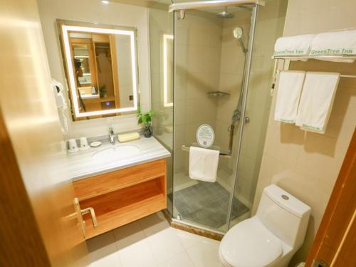 a bathroom with a shower and a toilet and a sink at GreenTree Inn Shangqiu Liangyuan District Suiyang Avenue Hotel in Shangqiu