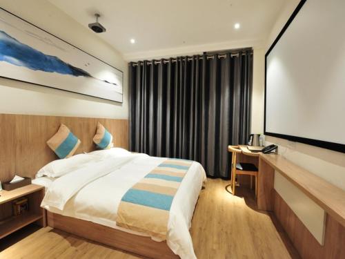 a bedroom with a large bed and a flat screen tv at VX Zibo Zhangdian District Jinjing Avenue Hotel in Zibo
