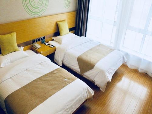 a hotel room with two beds and two windows at GreenTree Inn HuaiAn Area for development Shenzhen East Road Express Hotel in Huai'an