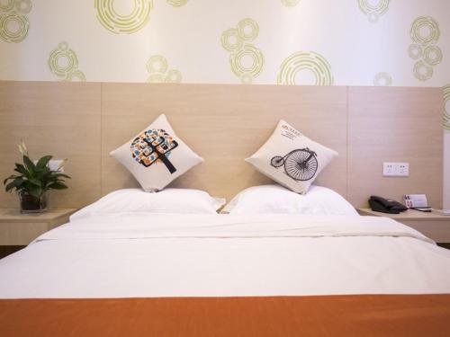 Un dormitorio con una cama blanca con almohadas. en Shell Huaian Xiamen Road Hotel en Huai'an