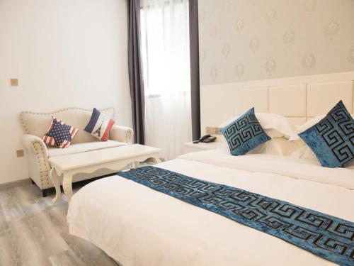 a bedroom with two beds and a chair and a couch at Shell Wuxi Huishan DistrictWanda Plaza Yanqiao Subway Station Hotel in Wuxi