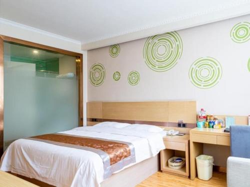 a bedroom with a large bed and a blue chair at GreenTree Inn Gannan Hezuo Pedestrian Street Express Hotel in Hezuo