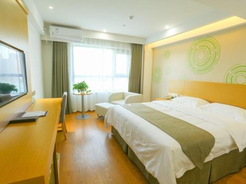 a bedroom with a large bed and a television at GreenTree Inn Shangqiu Liangyuan District Suiyang Avenue Hotel in Shangqiu