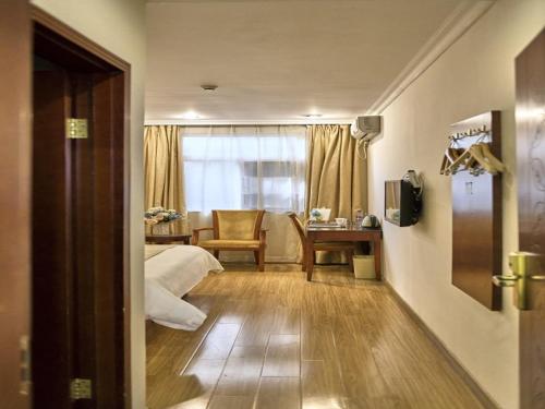 a bedroom with a bed and a table and a window at GreenTree Inn Guangdong Foshan Longjiang North Fenghua Road Express Hotel in Shunde